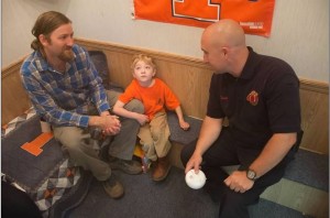 Gus (son of Harman Jordan, ROW Inspector) inspects the CFD Fire Safety House while Randy Smith discusses evacuation plans.